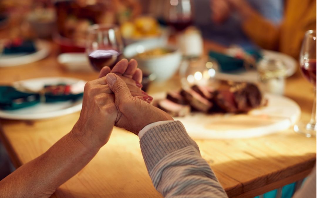 People, joined in hand around thanksgiving dinner table