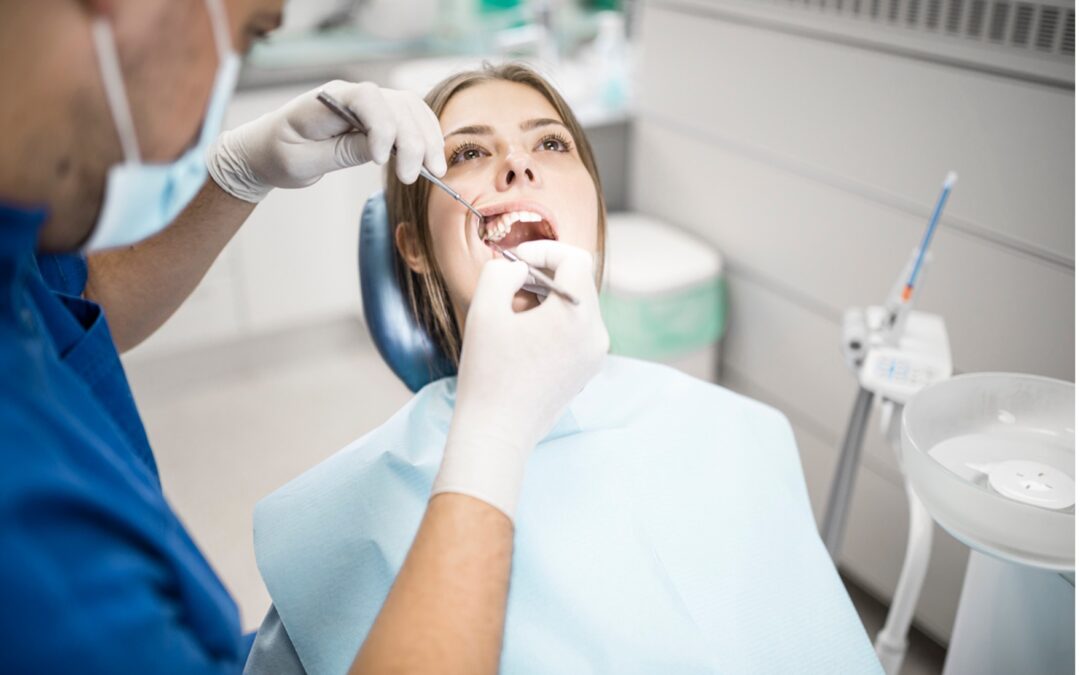 A dentist examining a person's teeth, Why Root Canal Retreatment May Be Necessary