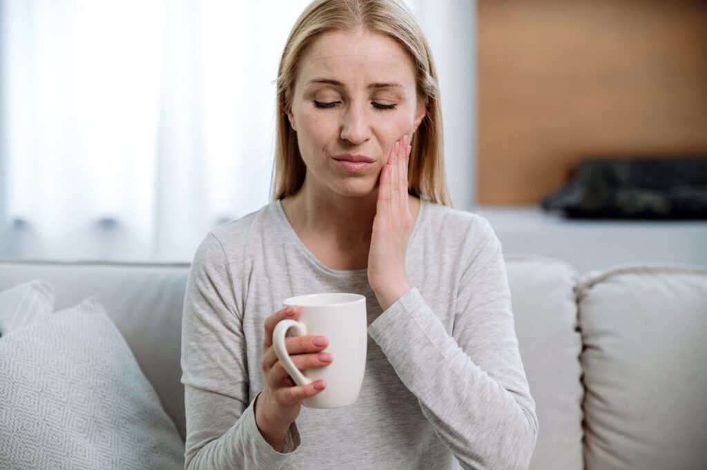 A person holding a cup and touching her face, Recognizing an Endodontic Emergency