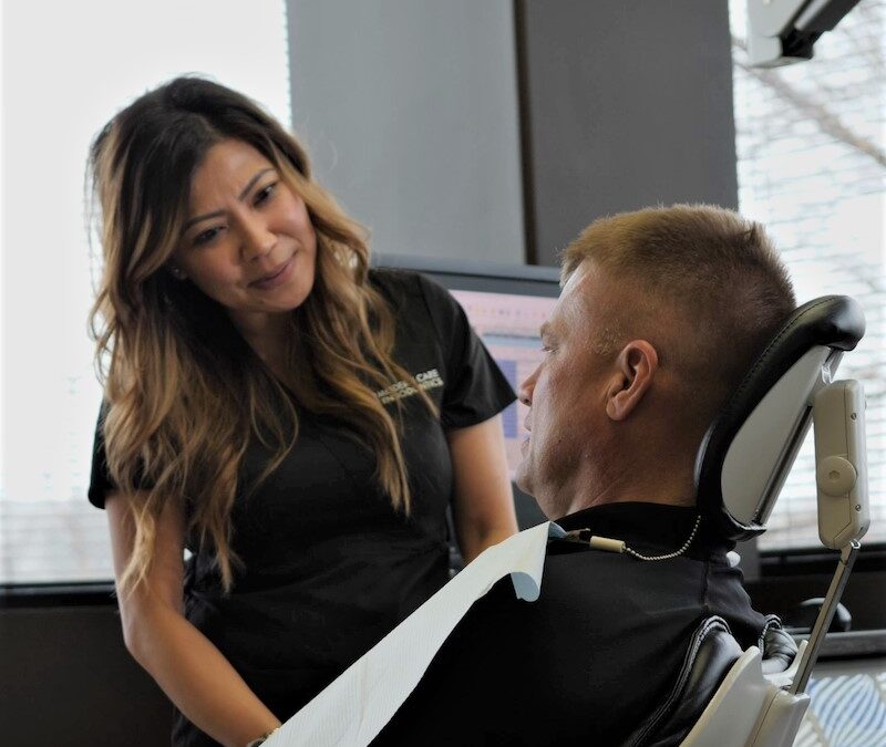 person listening to a person who is sitting in a dentist's chair, Root Canal FAQs: Understanding Endodontic Treatment for Saving Teeth