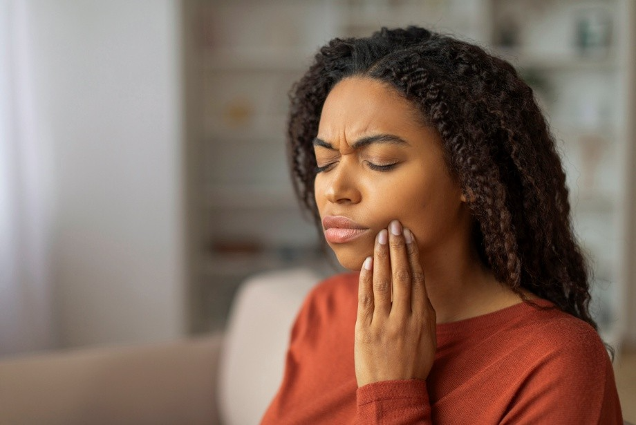 Woman holding her cheek in discomfort due to tooth pain